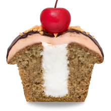 Load image into Gallery viewer, side view of half of a banana split cupcake with banana cake, marshmallow filling, and strawberry frosting, that has been dipped in ganache and finished with crushed peanuts and a maraschino cherry not-bg
